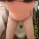 Emi squats over the toilet facing the camera in an orange top and shits into the bowl, snacking and talking to the camera as she goes. Vertical format video. Over 8 minutes.